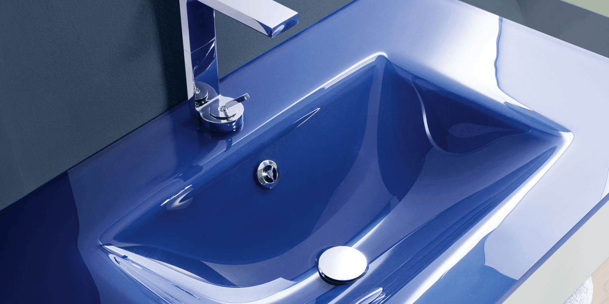 A blue glass countertop with an integrated basin with a drain and overflow