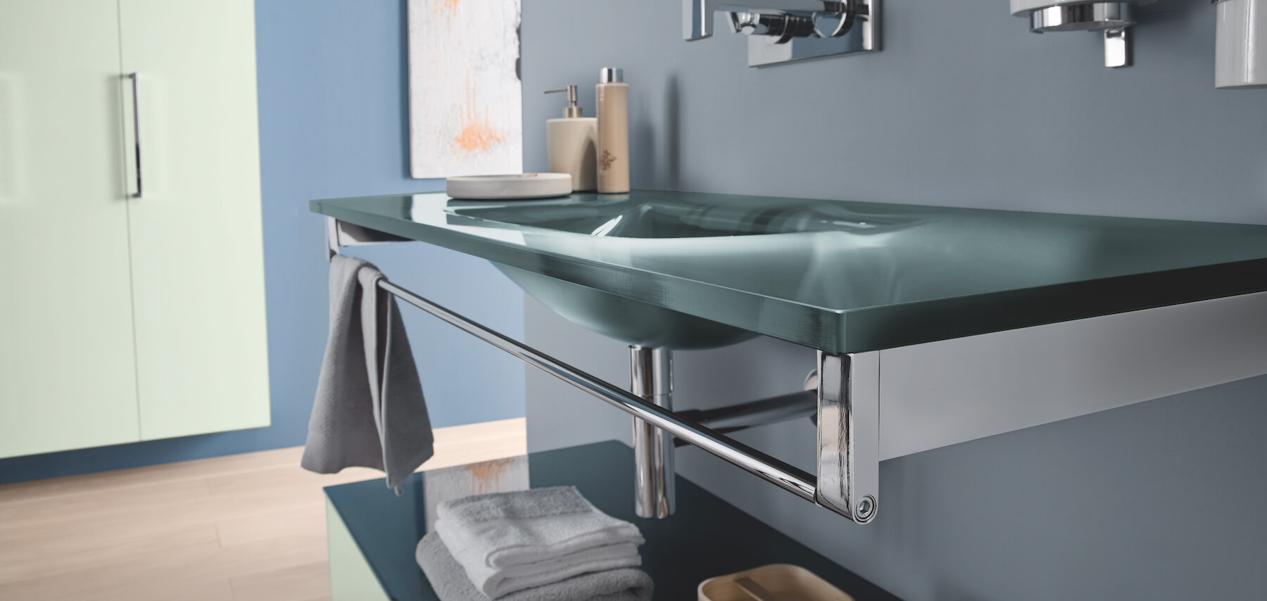 A glass bathroom countertop in blue with an integrated basin and towel bar