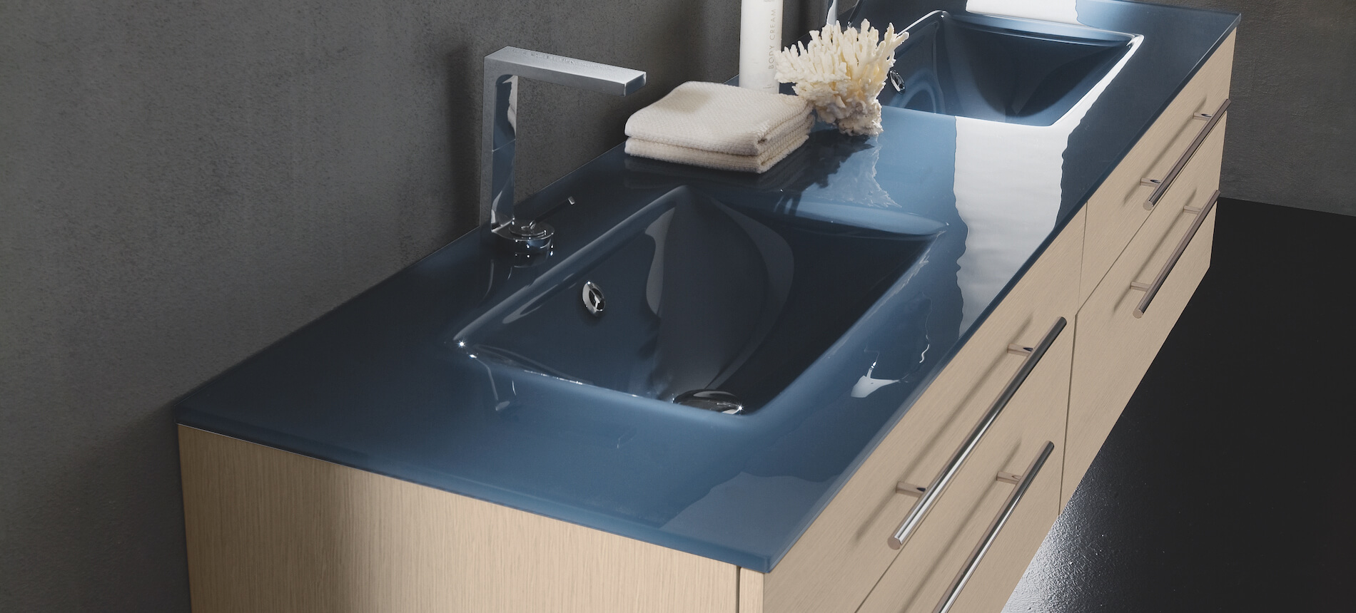 A double basin vanity with dark blue glass countertop