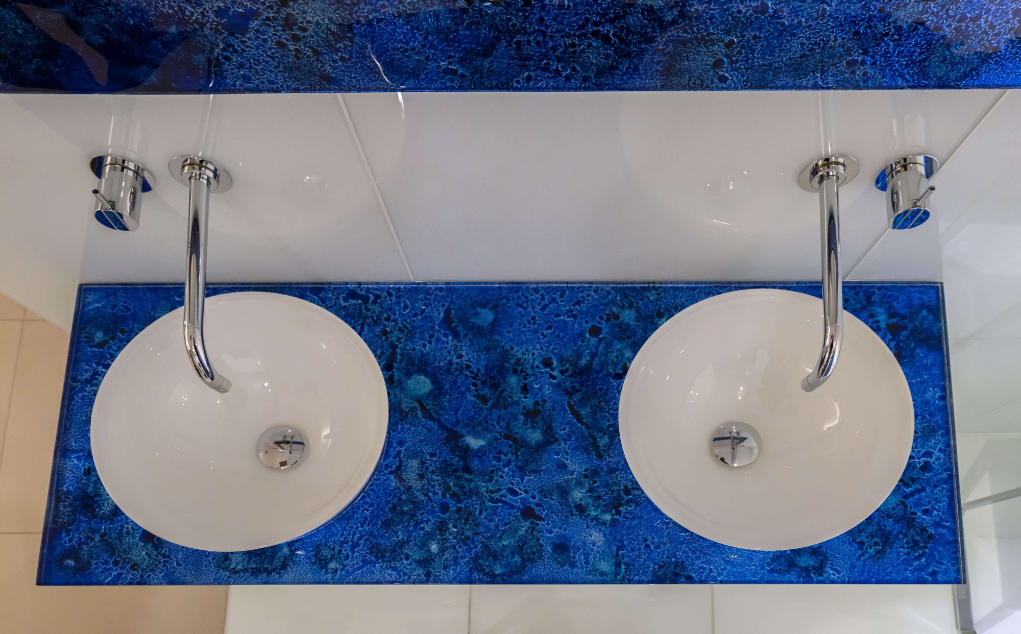Two basins on an ocean blue glass countertop