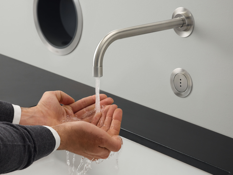 Closeup of someone washing hands with a wall-mounted touch-free VOLA faucet