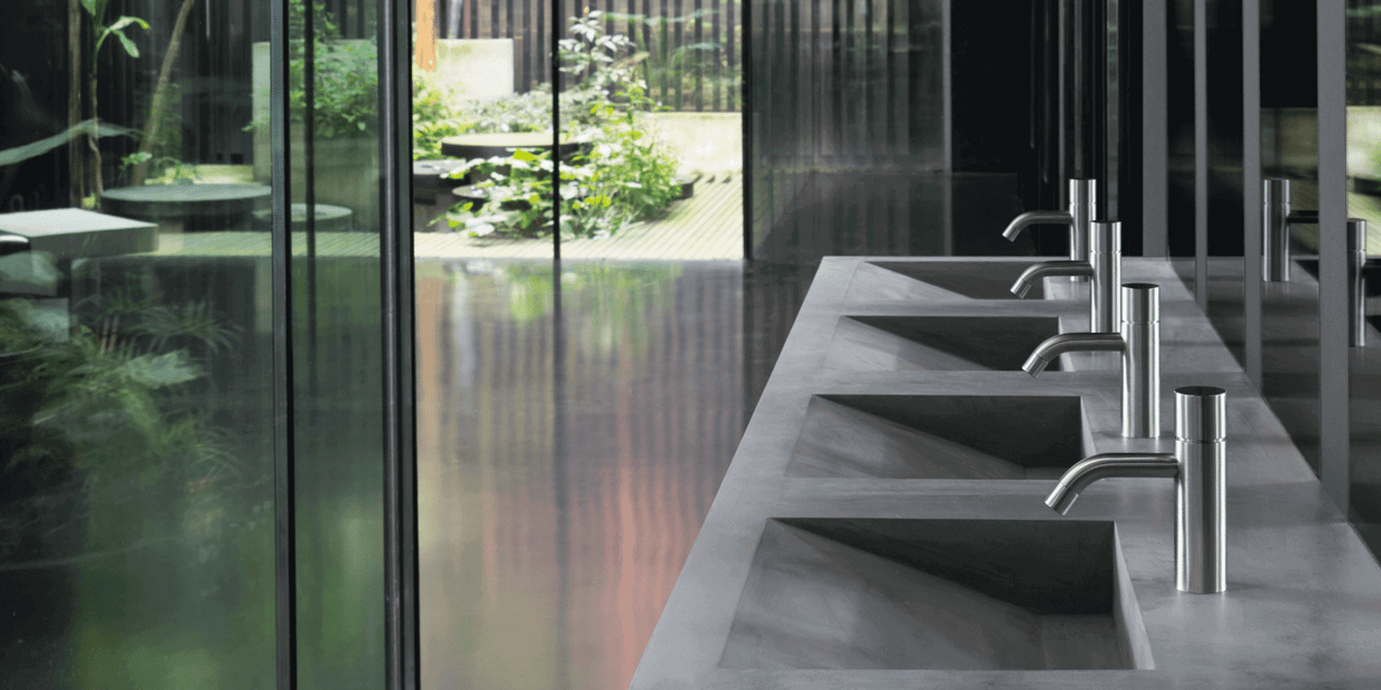 A row of VOLA faucets in a public restroom