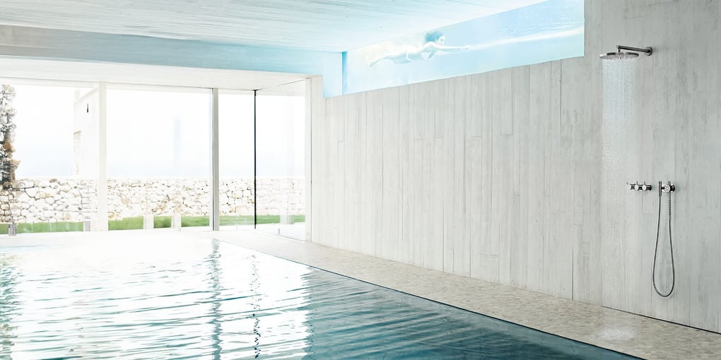 An indoor pool with a wall-mounted VOLA shower to the side
