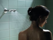 A person showering beneath a VOLA shower head