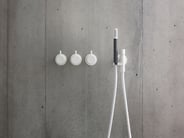 A matte white VOLA shower system mounted on a grey wall