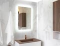 A rectangular mirror with integrated lighting and open shelving on the right, displaying decorative items above a sink.