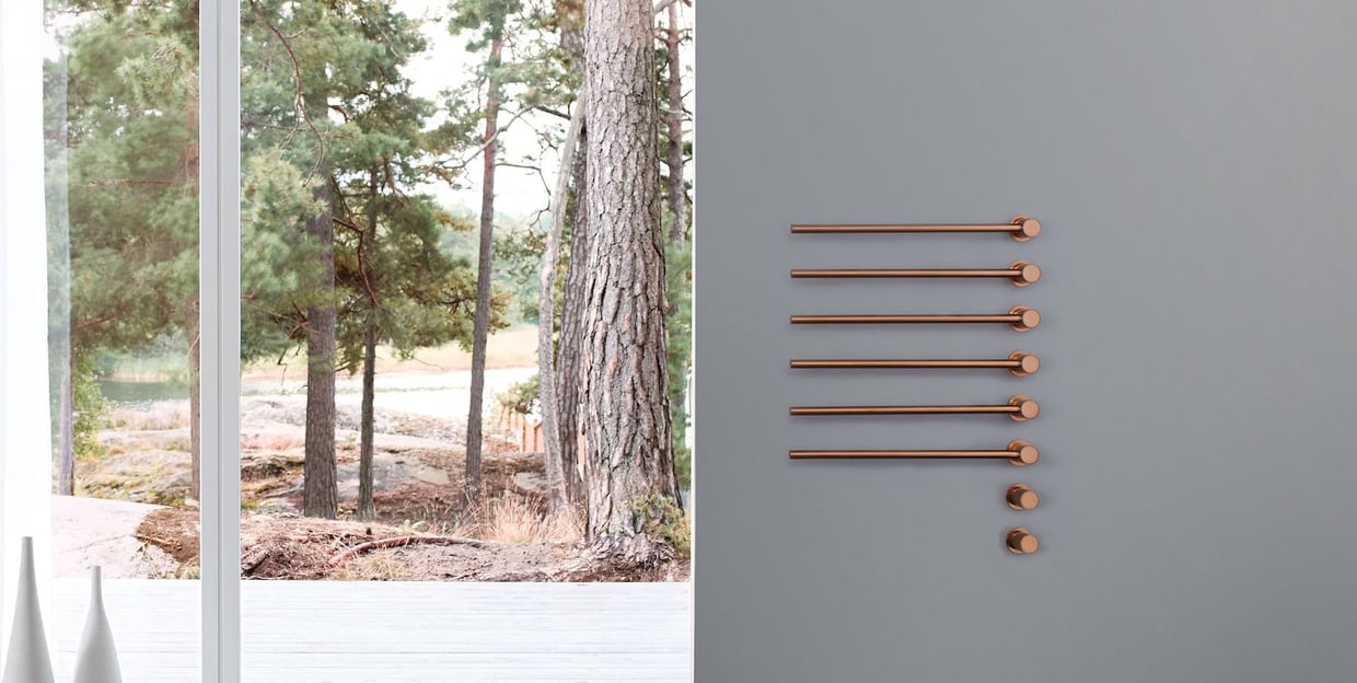 six copper VOLA towel warmer bars in a bathroom with a forest view