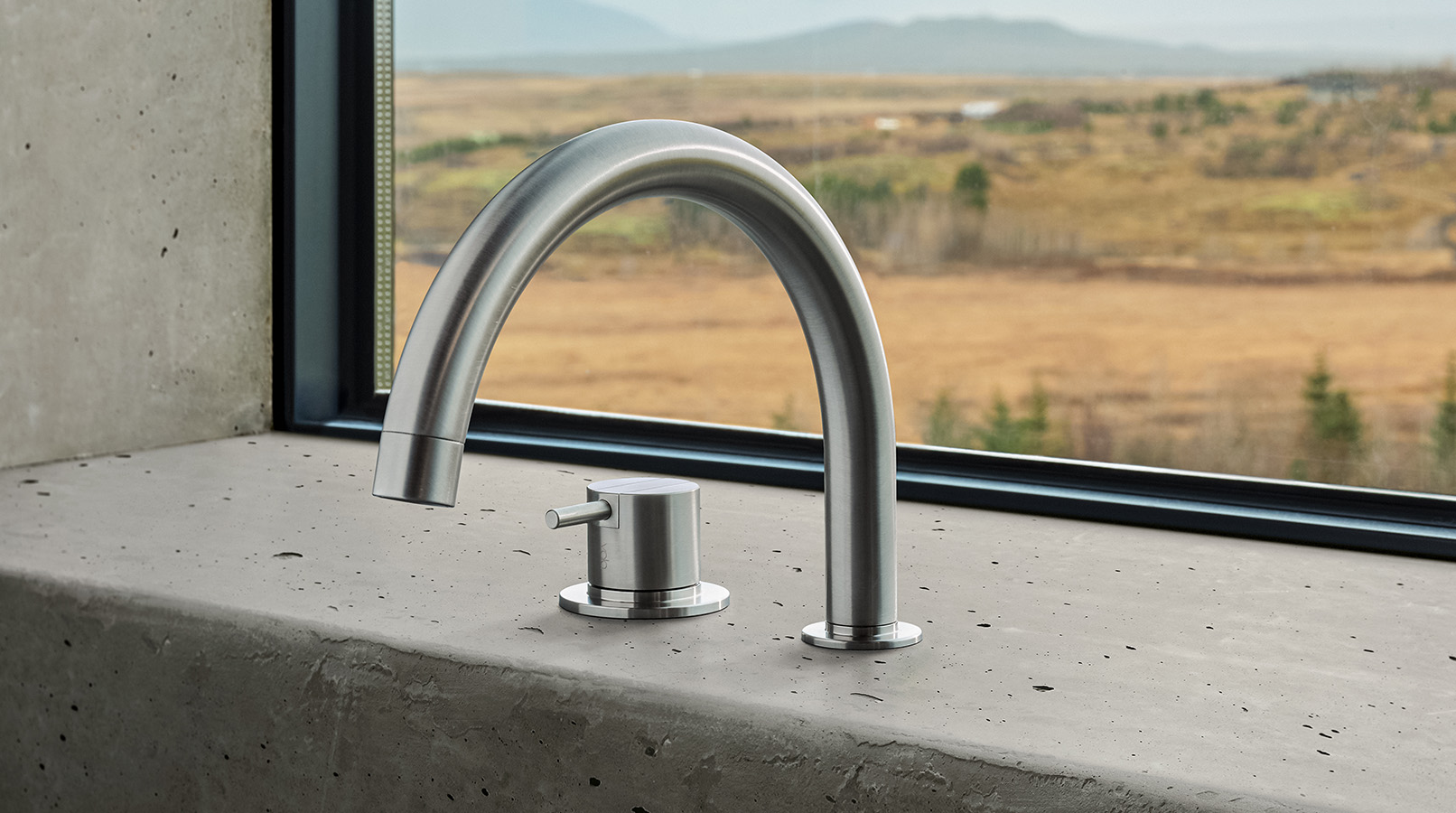 A VOLA tub filler mounted on a concrete surface